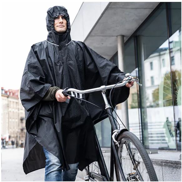 Чоловік в дощовику-пончо на велосипеді